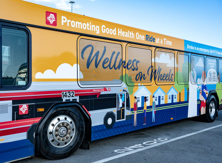 Colorful graphics on the side of the JTA and Baptist wellness on wheels bus.